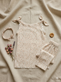 Baby girl floral outfit with shirt, trouser, and headband on a beige fabric background.